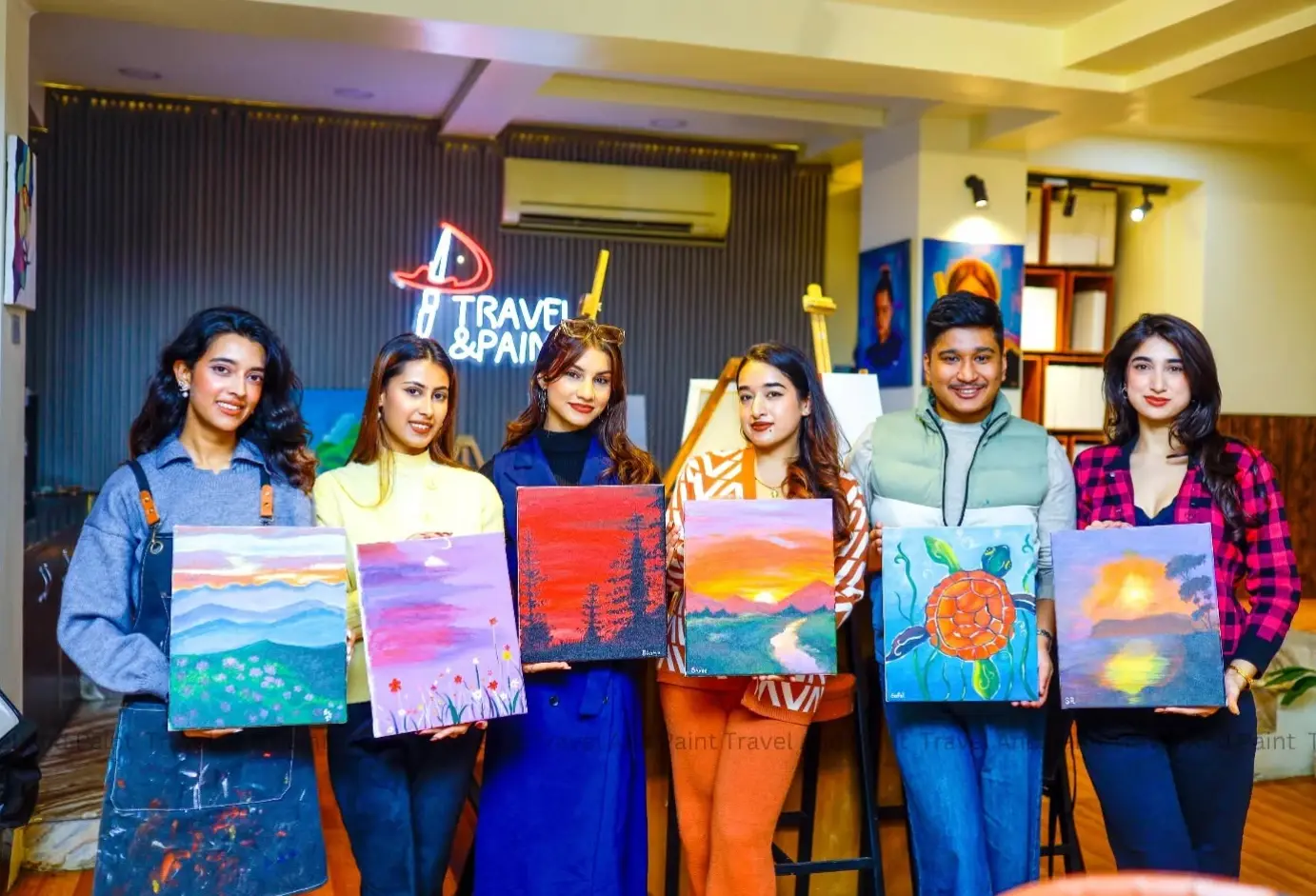A group holding vibrant sunset paintings at a painting party in Kathmandu