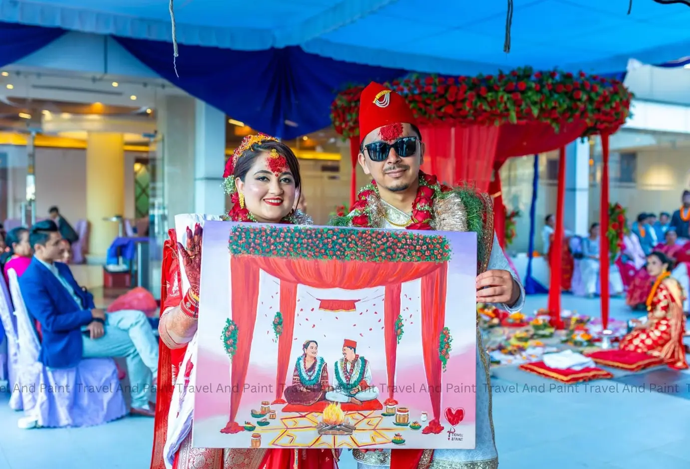 A couple in traditional Nepali wedding attire holding their live wedding painting at the venue in Nepal